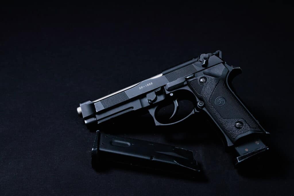 A black pistol with a magazine placed on a dark surface, illustrating essential tips for first-time pistol shooters.