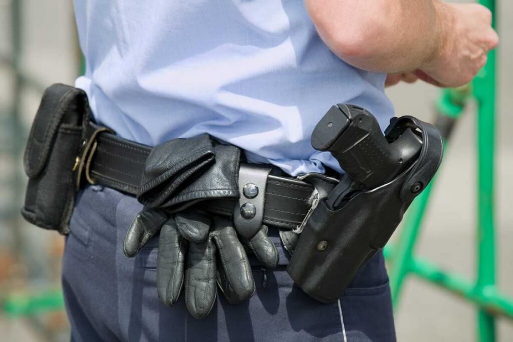 A close-up of an armed guard's belt with his weapon holstered.