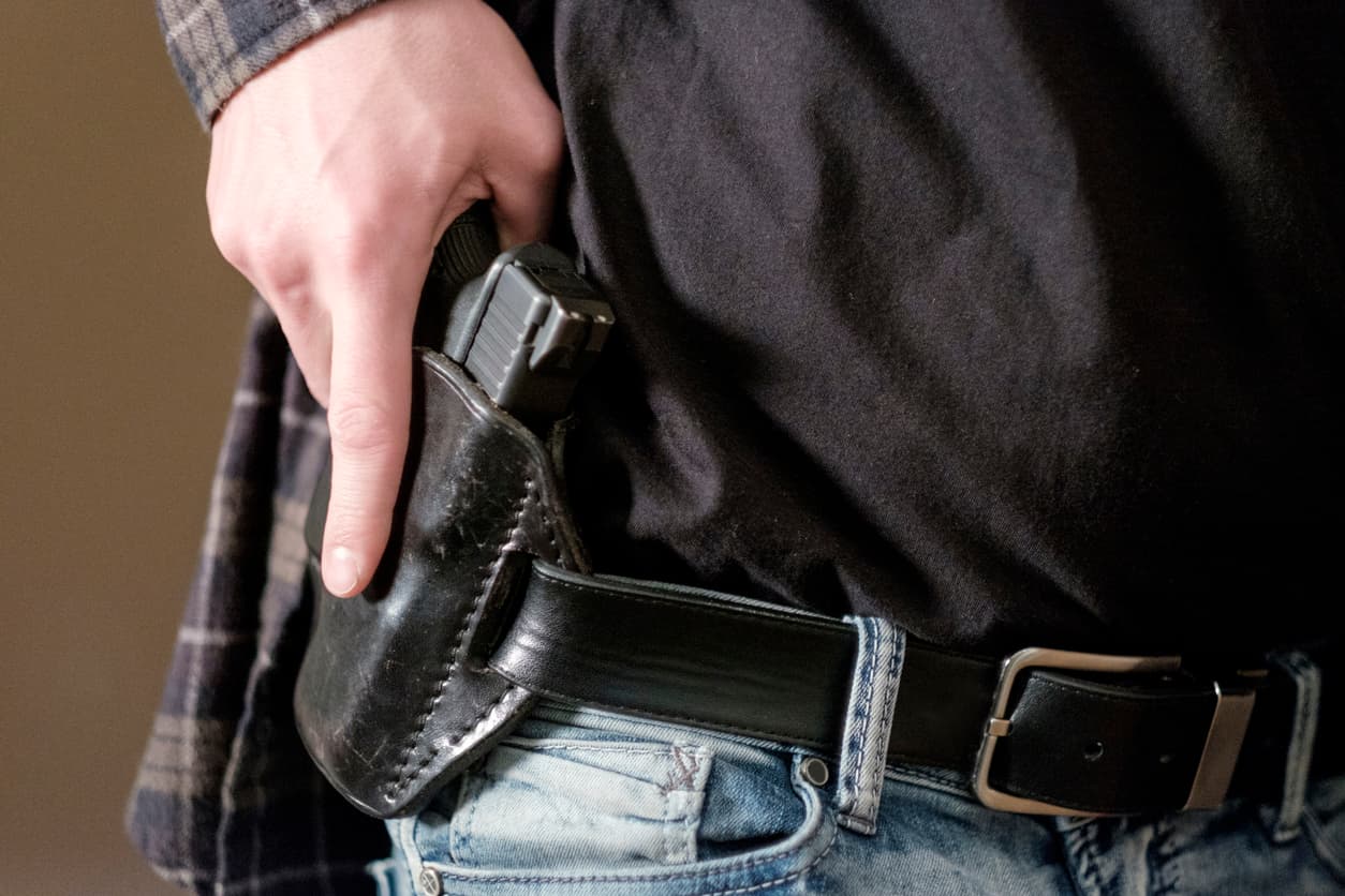 Person Holstering A Firearm, Representing How To Get A Ccw In Nevada With Proper Training And Legal Requirements.